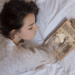 young girl holding a book on her hand while lying down on her bed mockup a14275